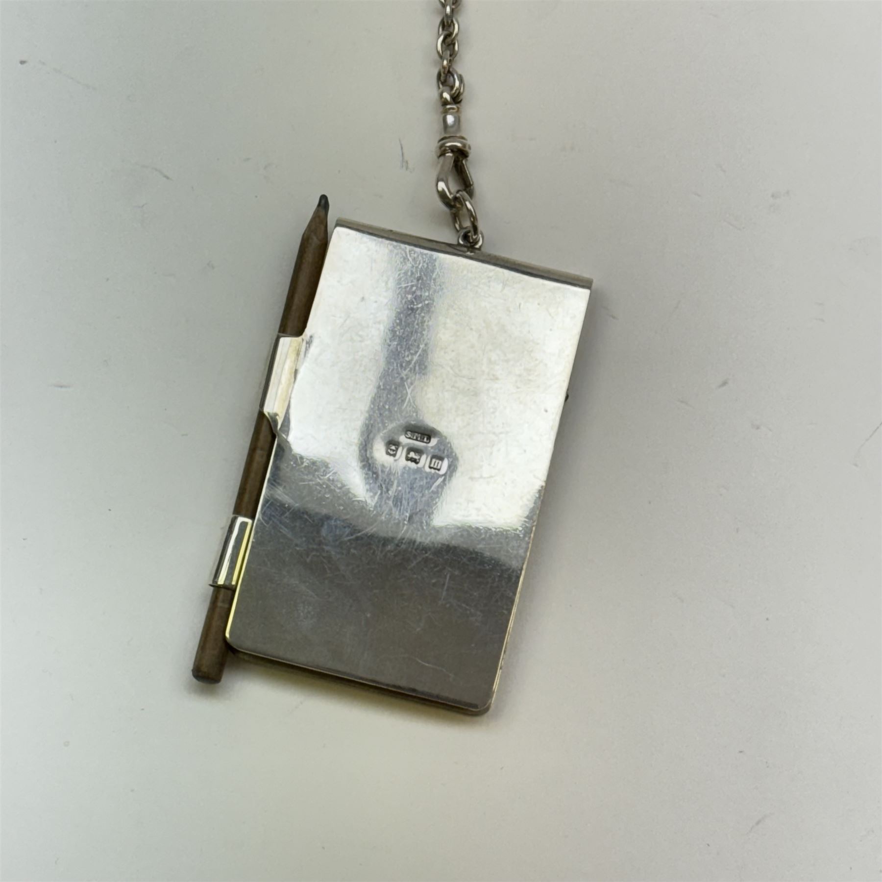 Victorian and later silver chatelaine, the shaped and foliate pierced clasp with embossed oval panel of a courting couple, hallmarked Levi & Salaman, Birmingham 1899, supporting six accessories on five chains: a circular mirror embossed with putti, hallmarked Henry Matthews, Birmingham 1911, pencil holder engraved with foliate scrolls, hallmarked Francis Webb, Birmingham 1914, conical scent bottle decorated with bamboo, (unmarked but testing as silver), aide memoire embossed with putti, hallmarked Samuel M Levi, Birmingham 1911, tape measure of compressed spherical form, hallmarked Henry Matthews, Birmingham 1899, and a purse with embossed putti, hallmarked Birmingham 1909, makers mark worn and indistinct, at longest point L31cm

