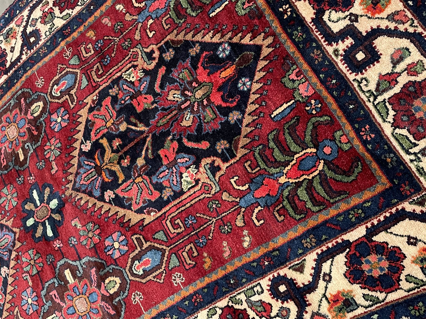 Persian Hamadan rug, the red ground field decorated with two floral medallions and stylised flower heads, repeating guarded border
