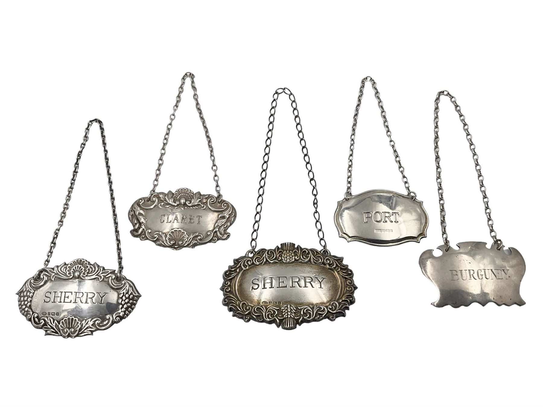 Five modern silver decanter labels, to include two sherry examples, embossed with scrolls and fruits, hallmarked W I Broadway & Co, Birmingham 1991 & 1997, a similar claret example, hallmarked S J Rose & Son, Birmingham 1973, and two plain shaped port and burgundy examples, hallmarked C Robathan & Son, Birmingham 1997 and A Haviland-Nye, London 1968