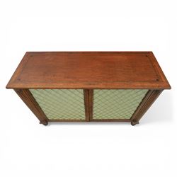 Late 20th century Regency style mahogany side cabinet, the rectangular crossbanded top with ebonised line inlay, above a pair of brass lattice grille doors with pale green fabric backing enclosing a shelved interior and two frieze drawers, flanked by reeded corner pilasters, upon turned tapering feet
