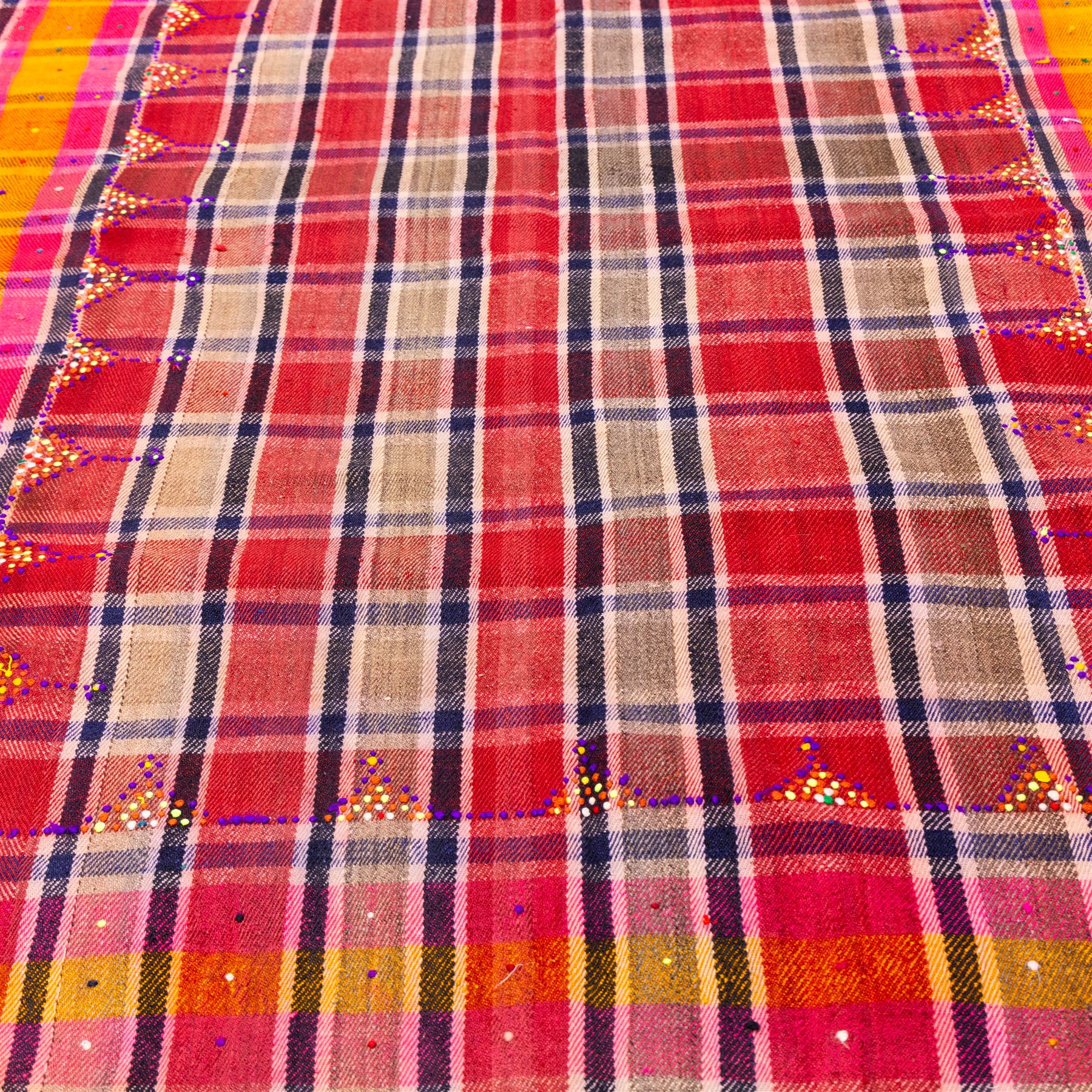 South West Persian Jajim kilim, field woven with a plaid design of intersecting bands in shades of red, terracotta, pink, and ochre, flanked by contrasting side panels decorated with small geometric tribal motifs the decoration incorporating raised wool details against flatwoven ground  