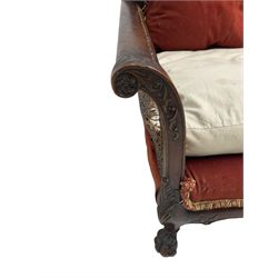 Early 20th century bergère three seat settee, shaped shell carved cresting rail, double caned back and sides, scrolled upright arms and shaped apron carved with shell and foliage, on hairy paw carved feet