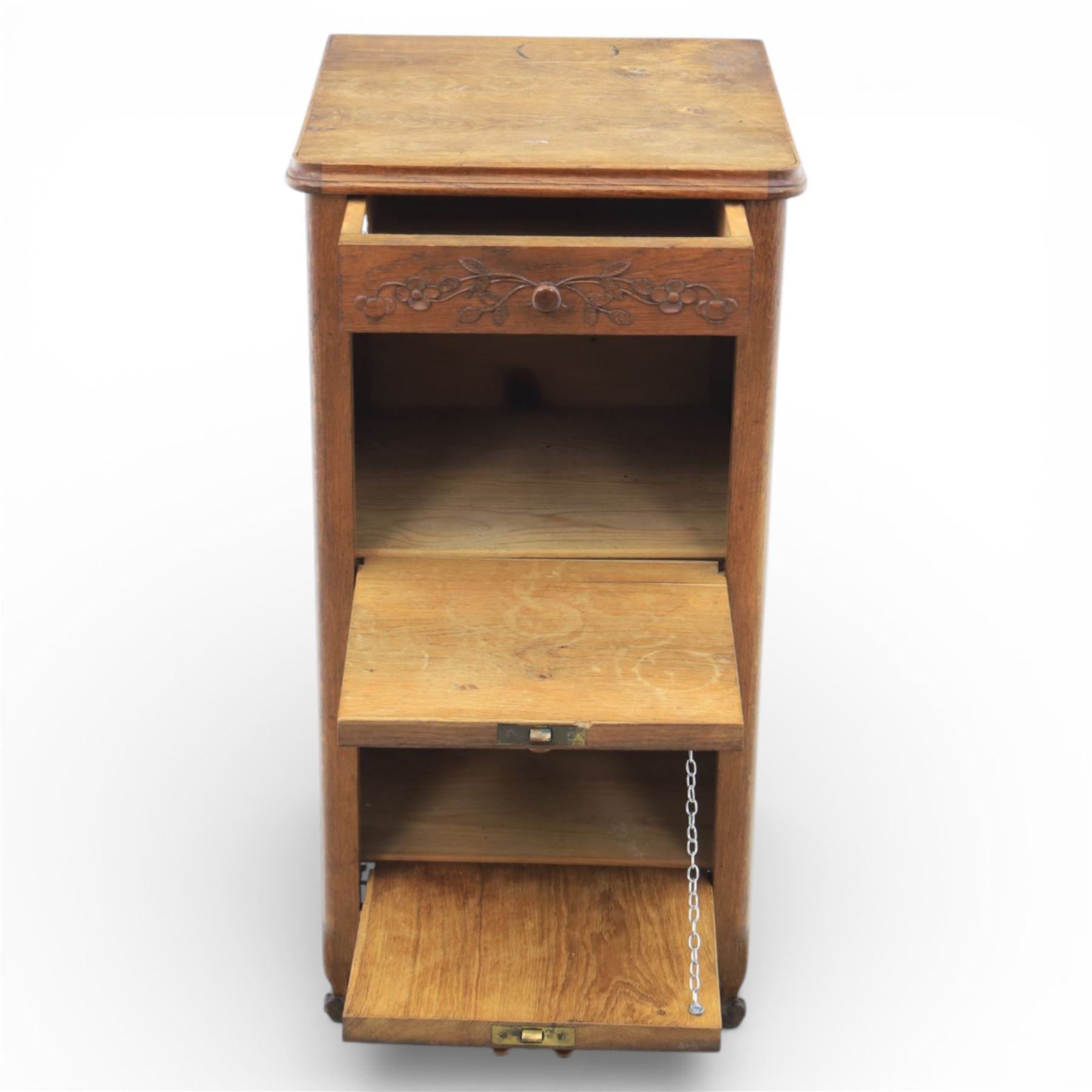 20th century French style oak bedside chest of pedestal form, the top with rounded moulded edge with drop leaf to the back, above five carved drawers with applied scroll ornament and turned knobs, the cupboard base with twin carved doors with diamond lattice panels, with shaped apron and bracket feet