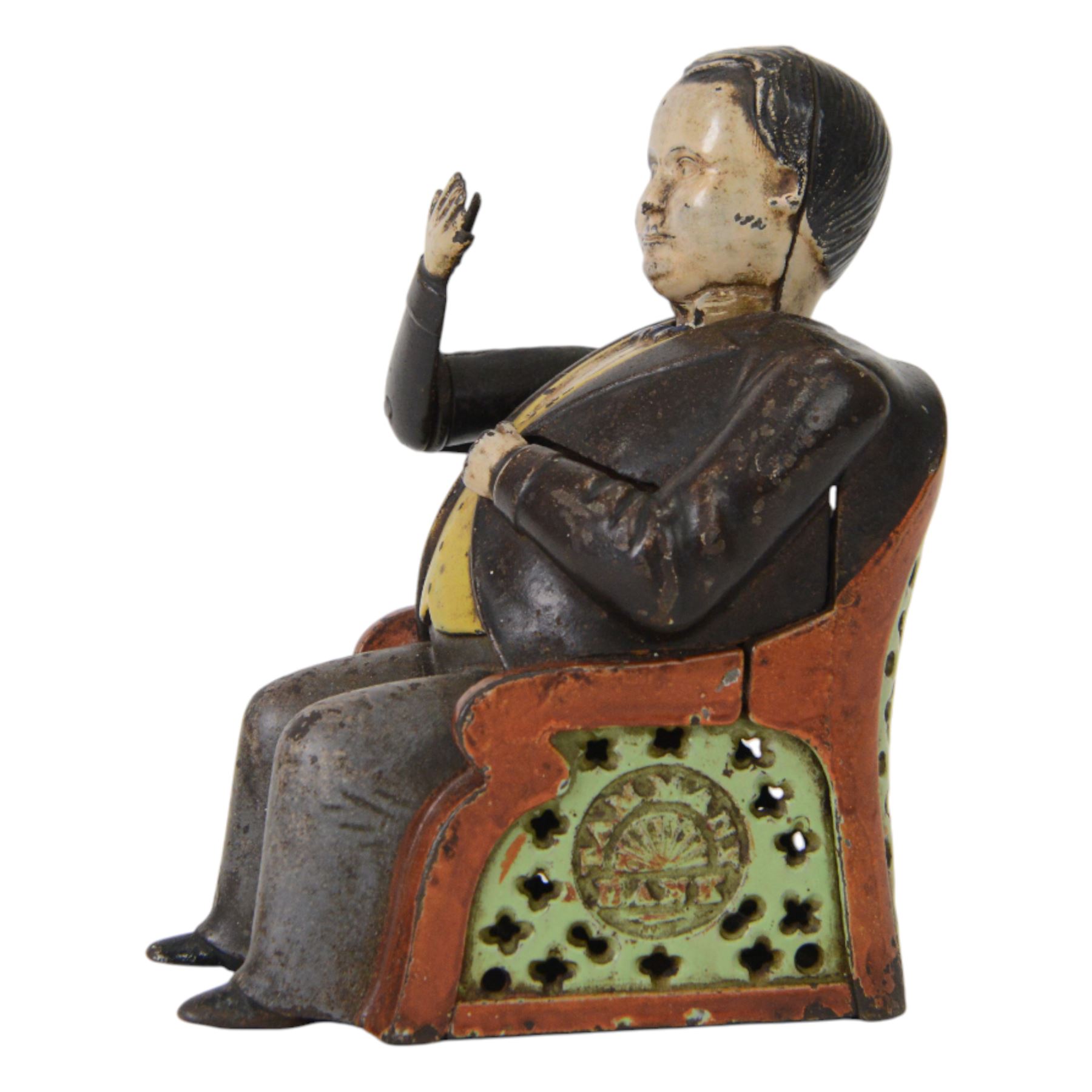 Late 19th century American cast iron Tammany mechanical money box, modelled as a suited gentleman with yellow waistcoat seated in a red and green chair, with two patent marks for Dec 23rd 1873 and June 8th 1875, H14cm