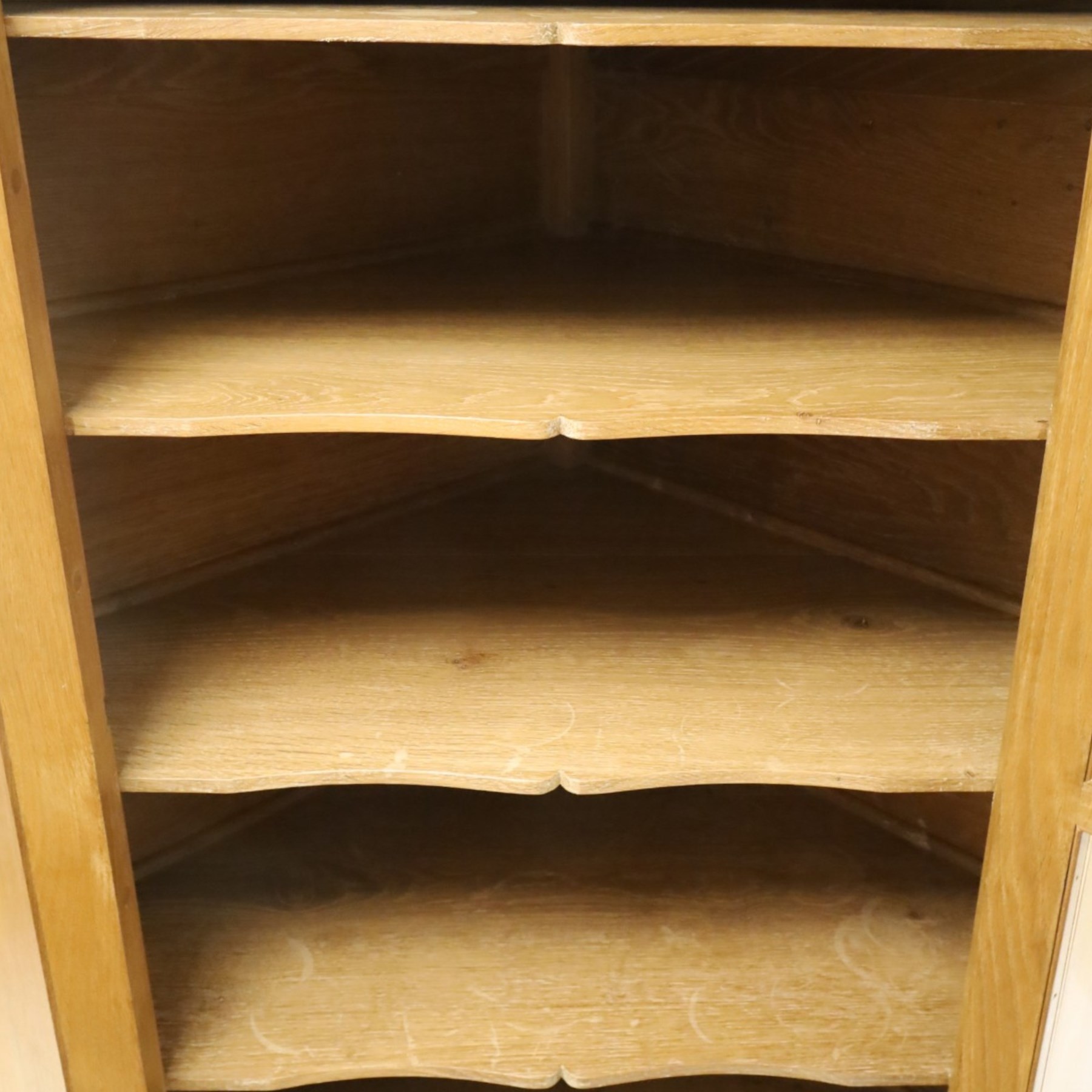Acorn Industries - oak floor-standing corner cabinet, the top fitted with astragal glazed door enclosing four shaped shelves, the base with single panelled cupboard over two drawers, raised on four stepped feet, carved with acorn signature to top and base, by Alan Grainger, Brandsby