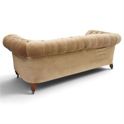 Victorian mahogany framed two seater Chesterfield settee, traditional shape with rolled back and arms over sprung seat, upholstered in buttoned-back neutral fabric, raised on turned front supports with ceramic castors