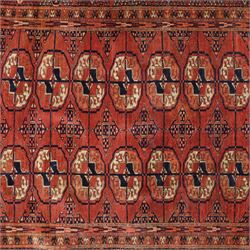 Central Asian Turkmen Tekke hand-knotted rug, madder red field decorated with rows of octagonal guls linked by secondary motifs within a dense geometric border, with fringe ends  