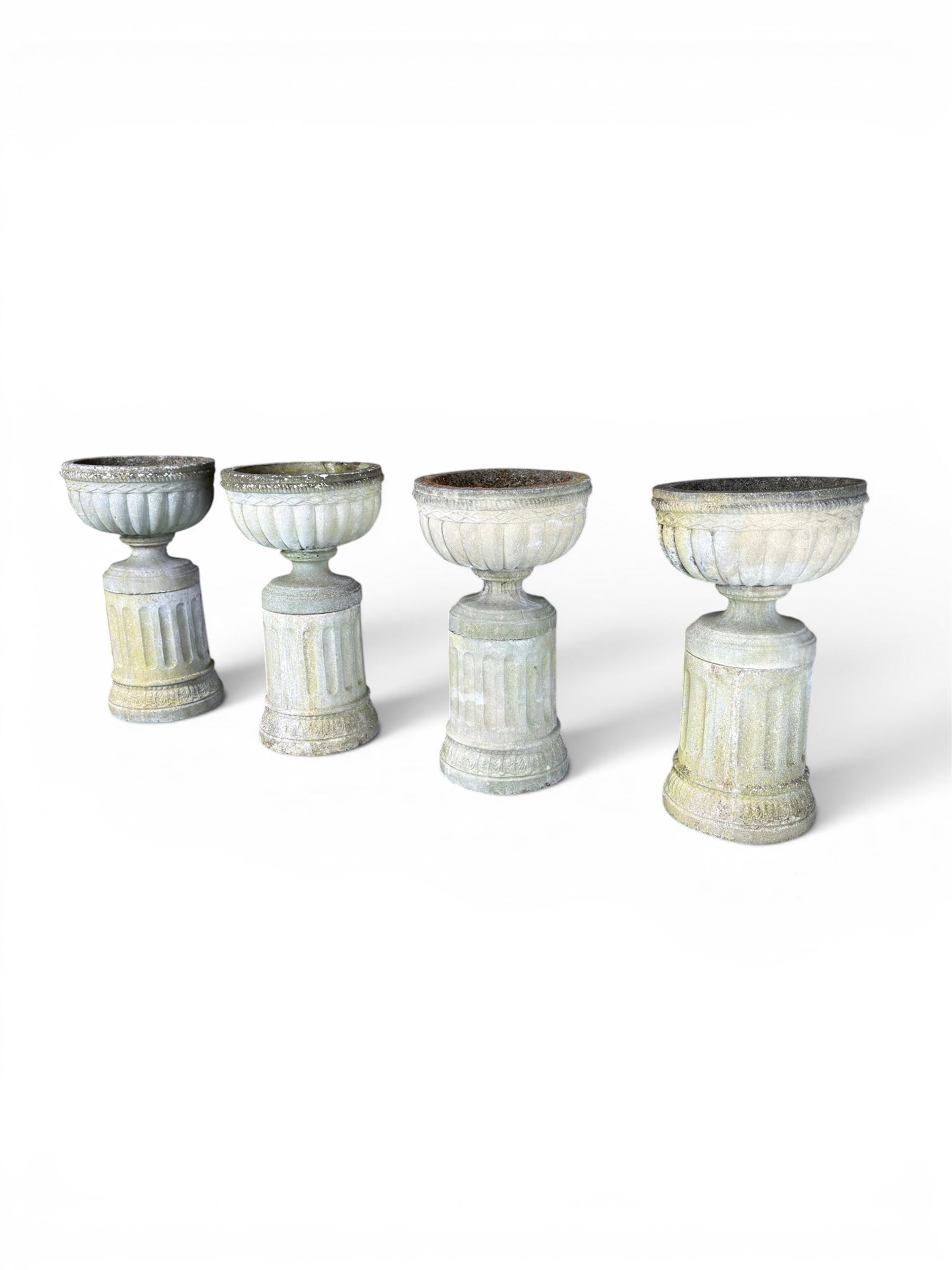 Four 20th century good quality weathered cast stone pedestal urns, circular lobed bowls with rope twist and lattice border, raised on squat base with fluted columns