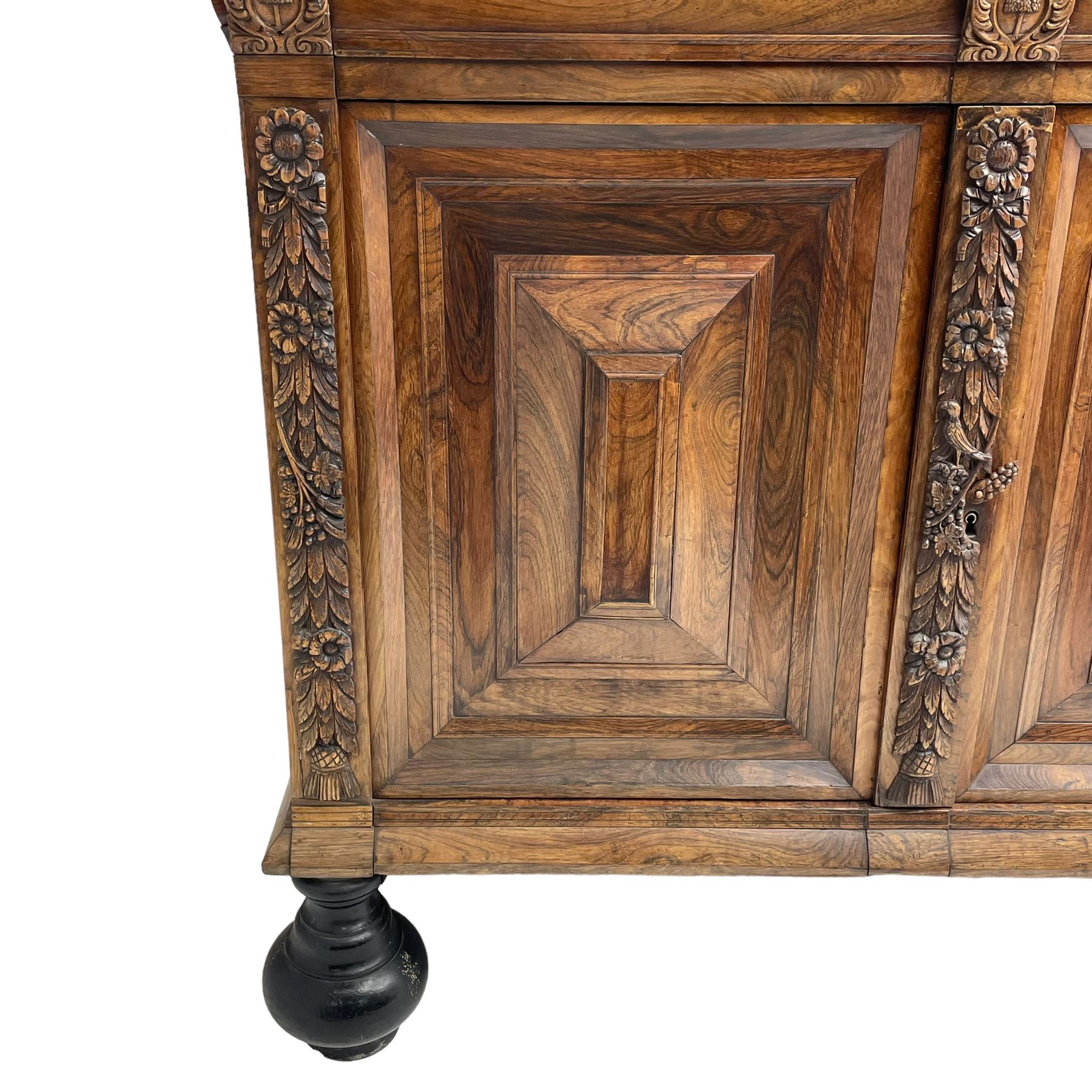 Late 17th century Flemish/Dutch rosewood and oak ‘Zeeuwse Kast’ or cupboard, projecting cornice carved with three putti masks, the uprights carved with lion masks over ribbons, flower heads and foliage, enclosed by four geometric panelled doors, lower central upright carved with flower head over foliate ribbon with bird among foliage, the escutcheon hidden by swivel berry carved cover, interior fitted with shelves, two drawers and shallow hinged cupboard, on two large turned and ebonised feet, circa 1680