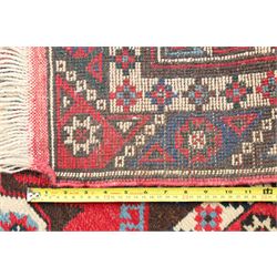 Two Persian rugs, Persian Hamadan hand-knotted rug, ivory ground centred by a terracotta medallion, surrounded by scrolling floral and foliate motifs, dark navy floral border with narrow guard stripes, fringed ends, H 176cm, W 75cm, Persian tribal hand-knotted rug, madder red ground decorated with three large geometric medallions, surrounded by angular motifs, enclosed by multiple geometric borders in dark navy, ivory and red, fringed ends, H 150cm, W 91cm