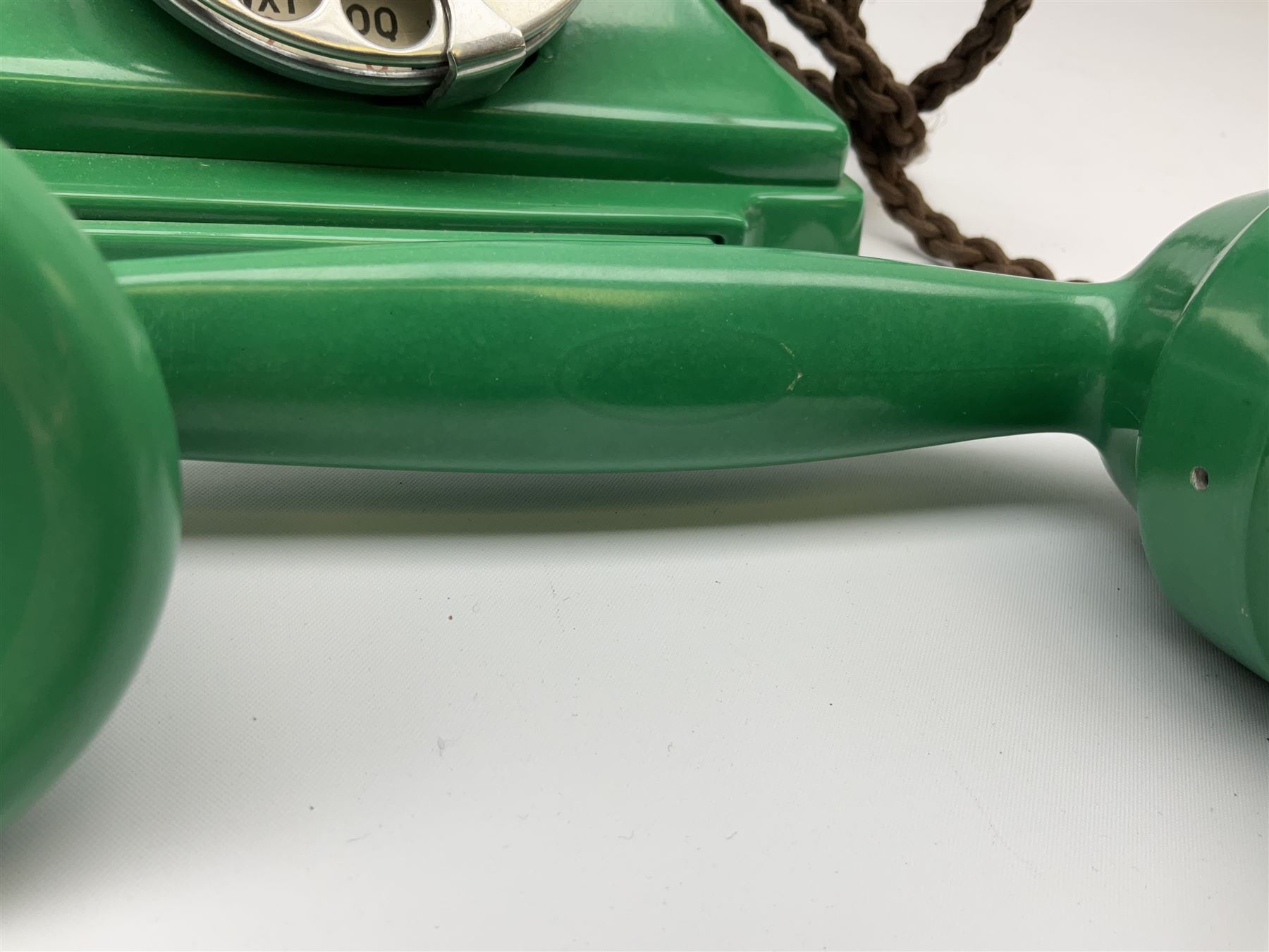Jade green Bakelite telephone, of pyramid form with rotary alphabet dial, brown braided handset cord and a base draw, W18cm D14cm H15cm