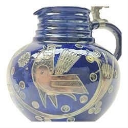 Wim Muhlendyck (1905-1986),  saltglaze stoneware jug of globular form with pulled and applied handle and ribbed neck with white cover, with stylised cockerels and flowers on a dark blue ground, with makers mark beneath, H22cm