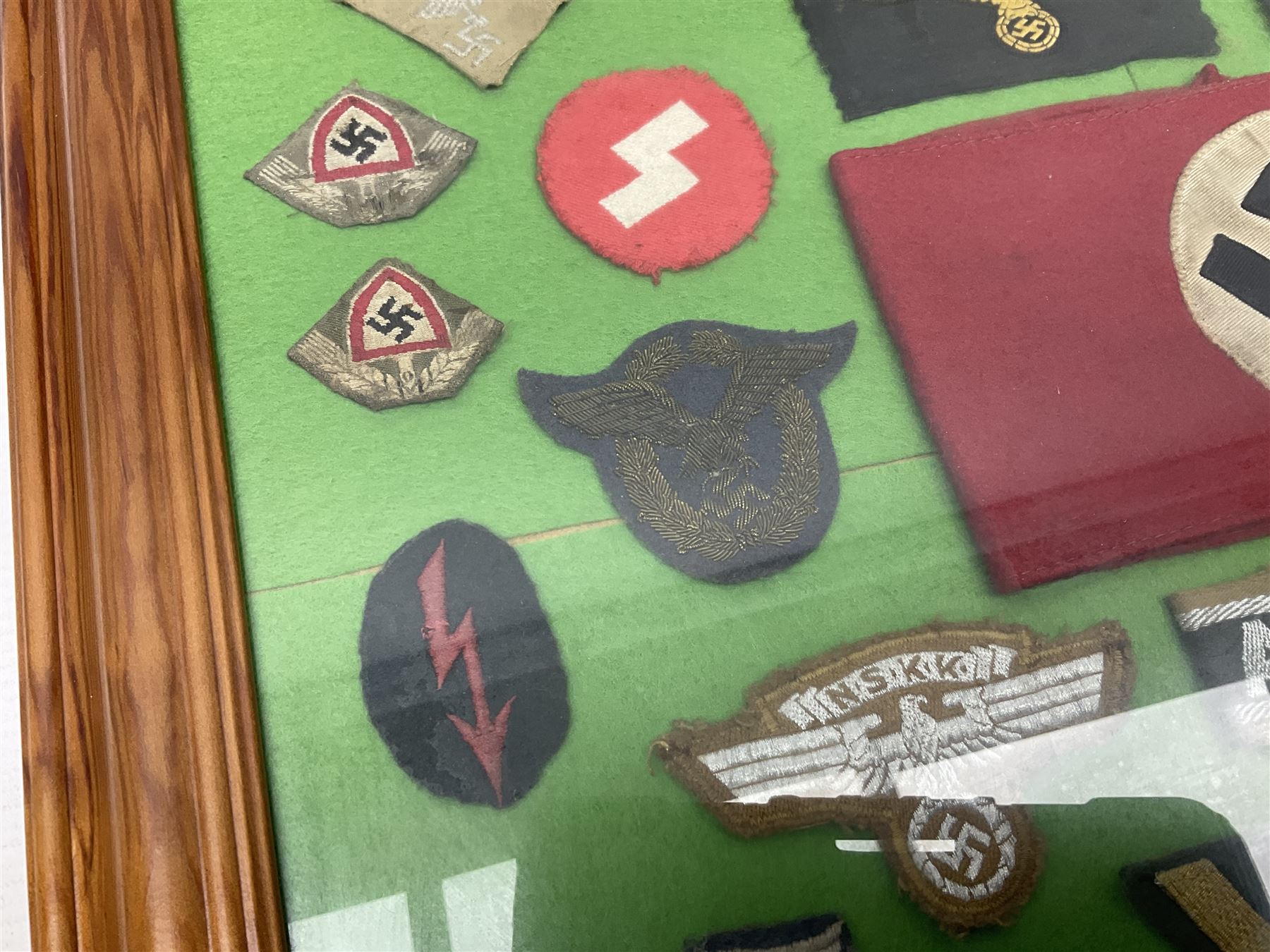 Framed display of thirty-four WWII German cloth badges including Luftwaffe pilot, Paratrooper, Afrikakorps cuff title, sleeve insignia for 'SS' Foreign Volunteers, various breast eagles including Luftwaffe, Army etc, RAD badges, Party Armband, rank and trade insignia, cap insignia etc; 40 x 50cm in modern pine frame