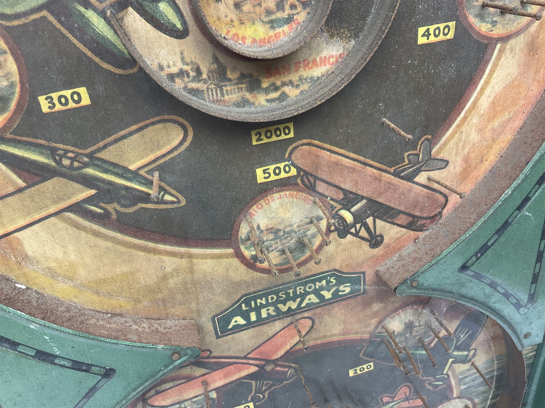 1934 Lindstrom's 'Airways' tin-plate bagatelle game by Lindstrom Tool and Toy Company Bridgeport Conn., the decorative bagatelle board depicting Lindstrom's epic airway routes; with wooden peg and quantity of balls H61cm