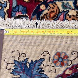 Large North East Persian Meshed hand-knotted carpet with signature, raspberry red field with central shaped cusped medallion, densely decorated with intricate arrangement of scrolling vines, and florals designs within conforming spandrels and a dark ground border richly ornamented with stylized flowers, vase and bird ornamentation, enclosed by guard stripes, with cotton fringe ends