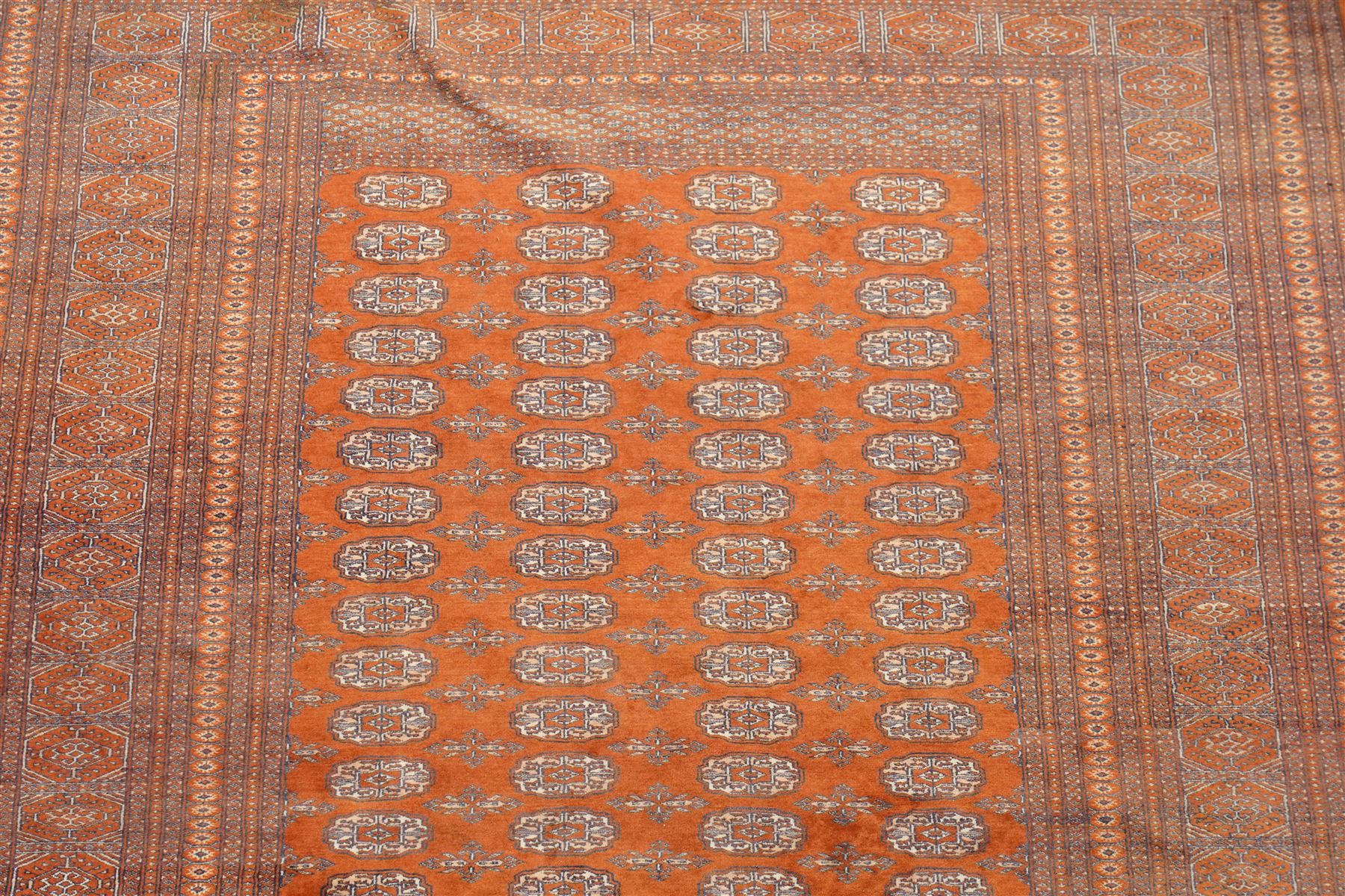 Bokhara hand-knotted carpet, terracotta ground with repeating rows of Tekke guls and geometric motifs, enclosed by multiple geometric borders, with silk highlights, fringed ends