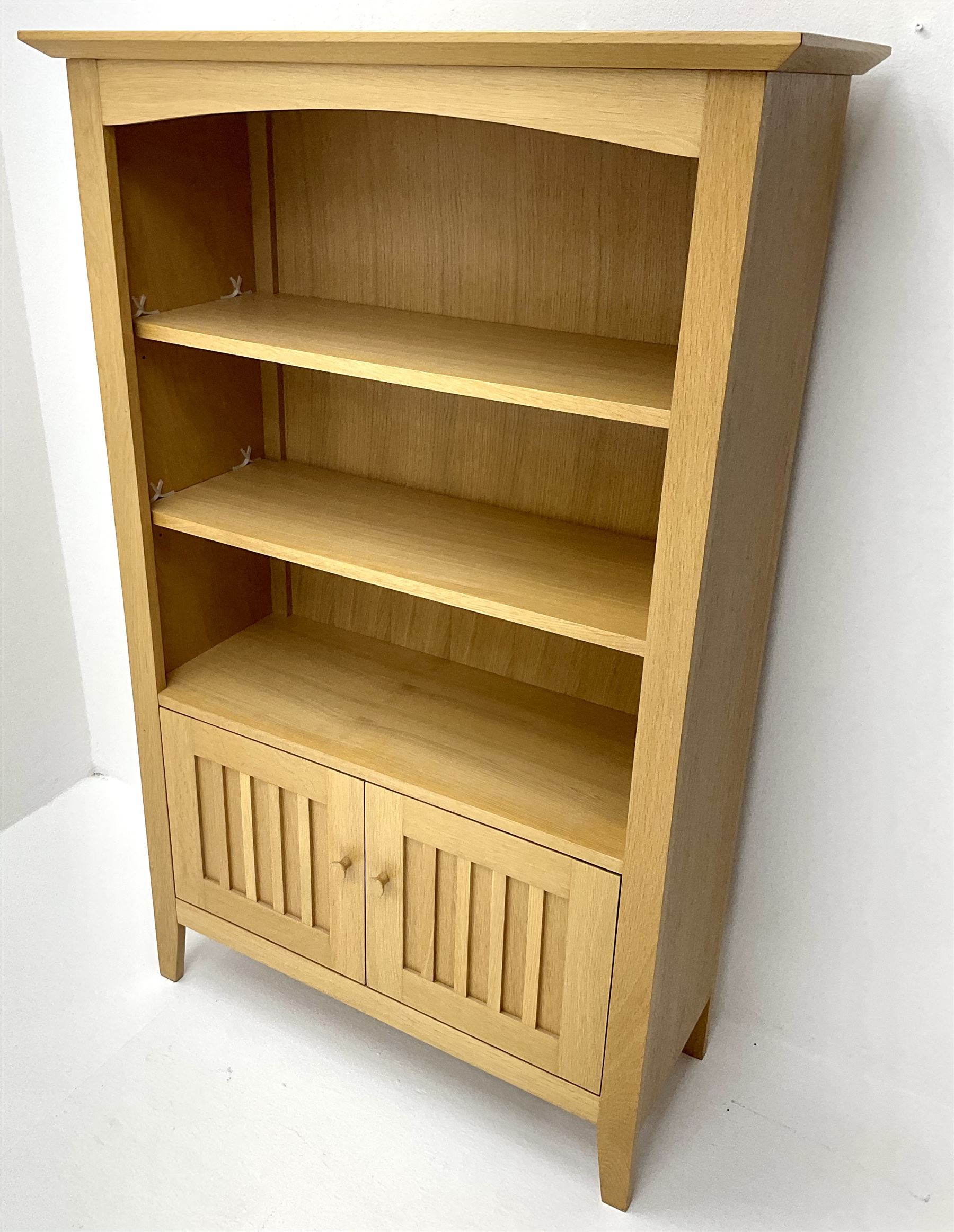 Light oak open bookcase, two shelves above two cupboard doors, stile