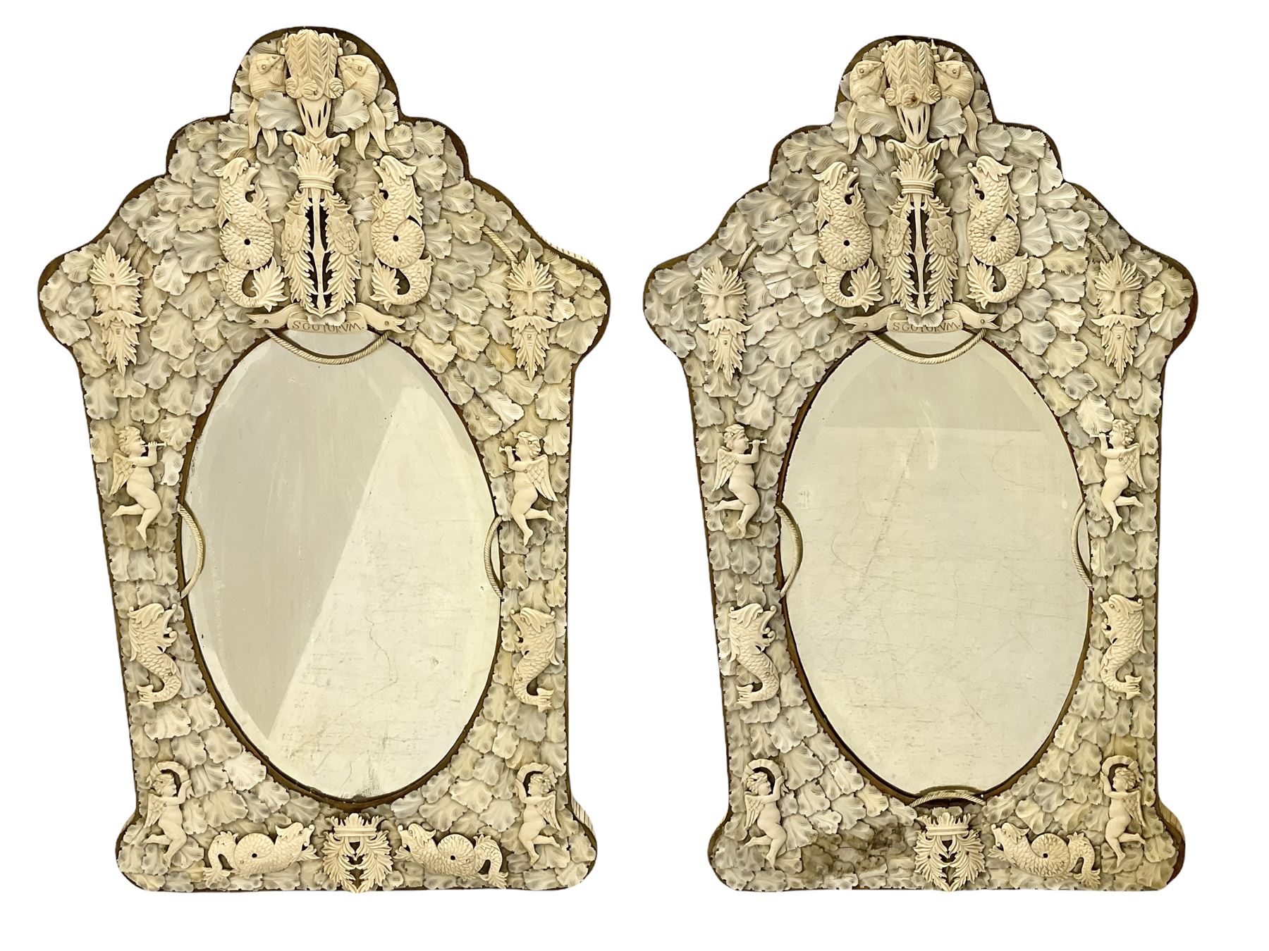 Pair 19th century French Dieppe bone and ivory wall mirrors, the oval bevelled mirror plates within rectangular frames with shaped tops, profusely decorated with ivory leaves, further detailed with carved bone armorial type crest inscribed 'SGOTORVM', putti, fish and mask heads, H81cm W48cm