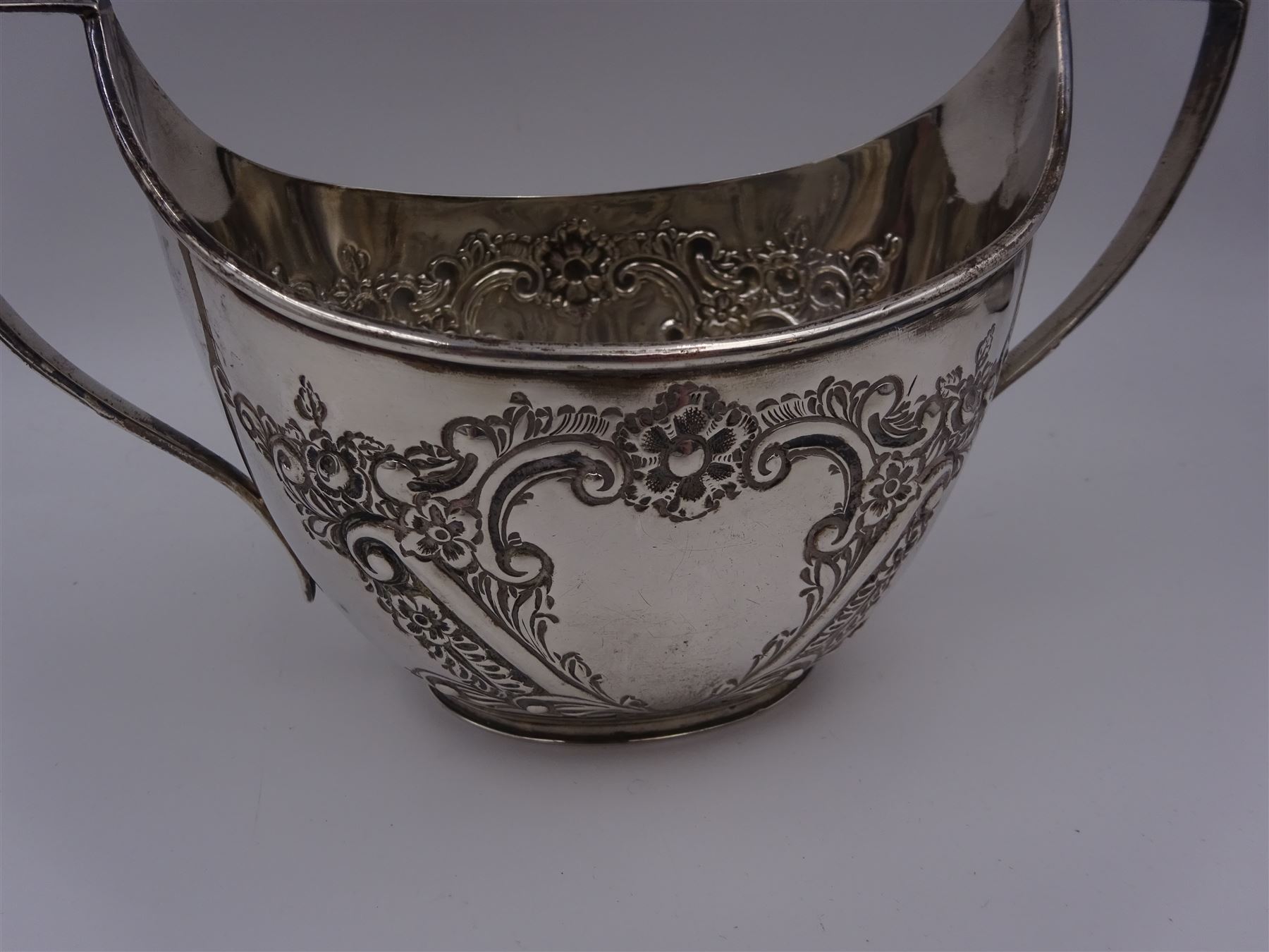 Late Victorian silver milk jug and twin handled open sucrier, each of oval form with angular handles and embossed floral, foliate and C scroll decoration, hallmarked James Deakin & Sons, Sheffield 1899, sucrier with handles H10.8cm