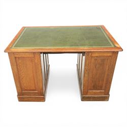 20th century oak compact pedestal desk, tooled green leather inset top, above a single frieze drawer, with a bank of four graduated drawers and a drawer and cupboard, panelled sides raised on castors