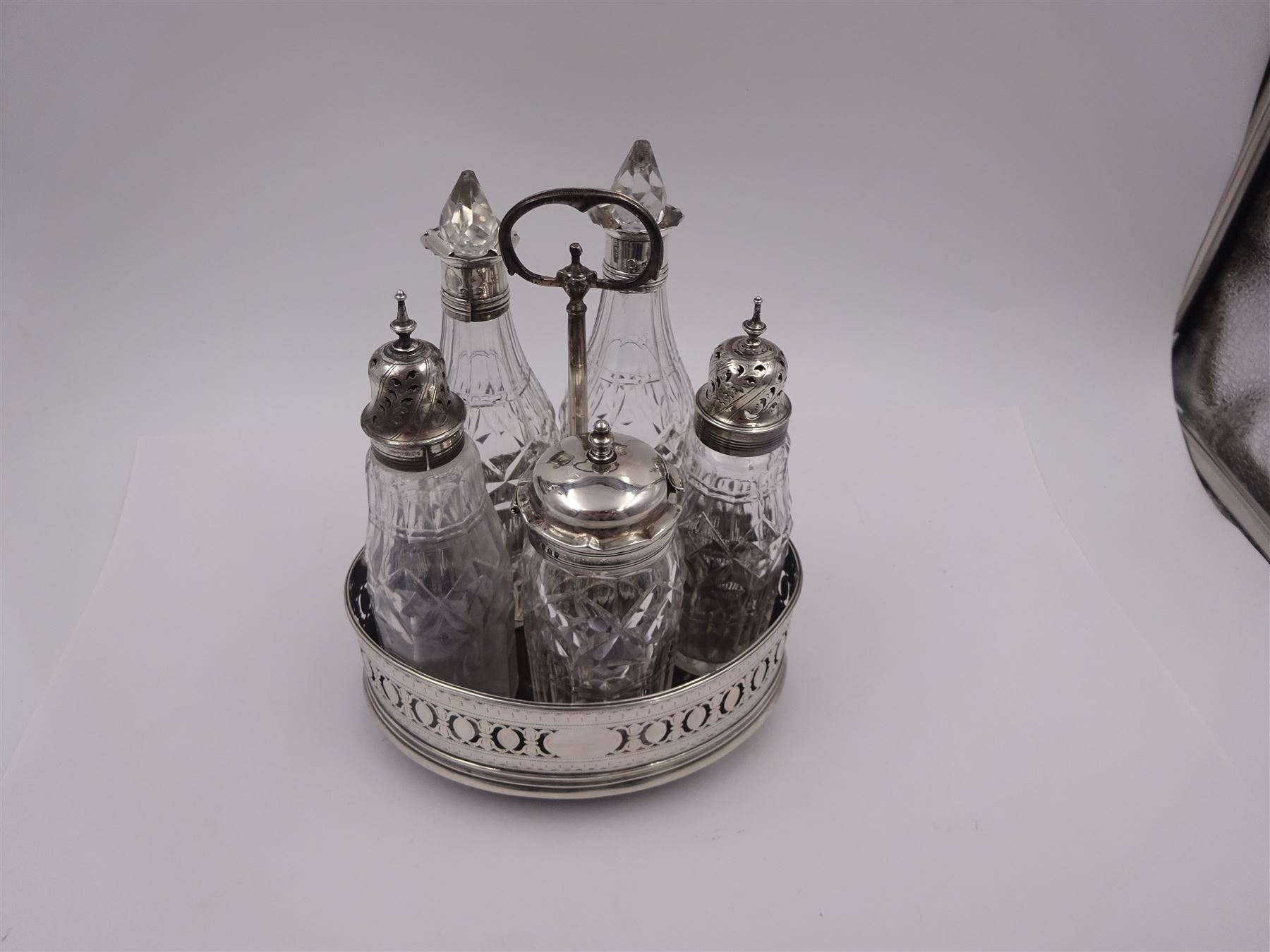 Late 18th century silver cruet stand, of oval form, with pierced sides upon four bun feet, hallmarked to handle Hester Bateman, all other hallmarks indistinct, together with five matched silver mounted cut glass cruet bottles, including some later Victorian examples, hallmarks predominantly indistinct, stand H20cm