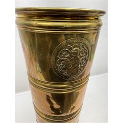 Brass stick stand, of tapering form, with circular embossed knight and shield crest, H55cm