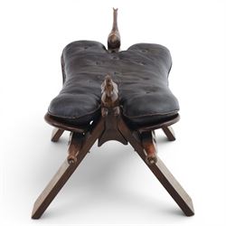 20th century saddle stool, wiht black leather seat, surmounted with carved horses, on an X-frame base with brass inlay