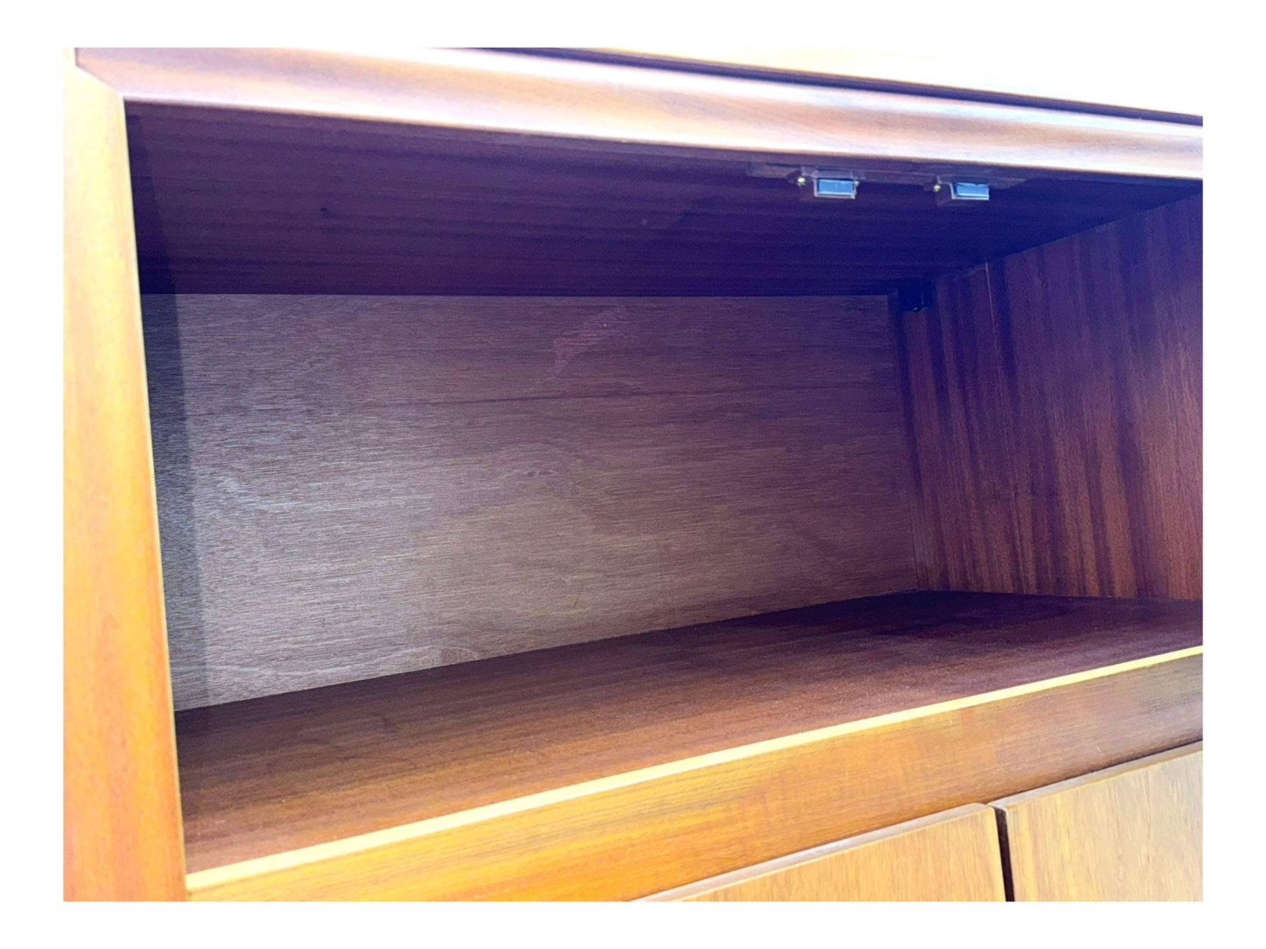 William Lawrence - mid-20th century teak double wardrobe, upper storage section over twin doors featuring recessed handles and contrasting horizontal panel, enclosing hanging rail compartment, towel rail, mirror, shelves and drawer, on plinth base with concealed castors