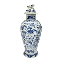  Late 19th/early 20th century Chinese blue and white vase and cover, of baluster form, the body painted with dragons amidst flowers, the domed cover with foo dog finial, with Kangxi character mark beneath, H22cm