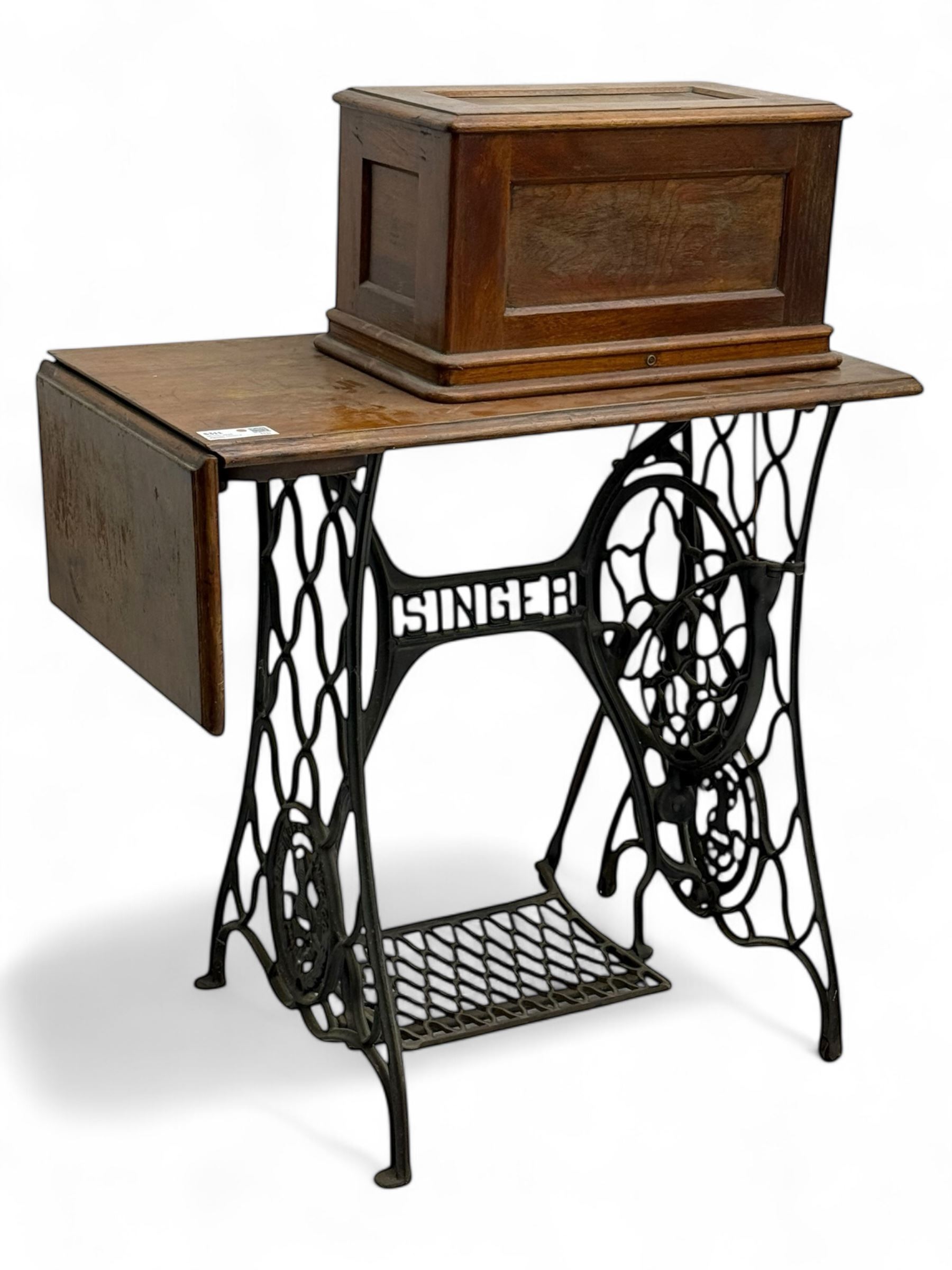 Singer - early 20th century cast iron treadle sewing machine, with hand crank wheel and oak work surface, the machine decorated with gilt foliate detail, complete with rectangular wooden cover and folding extension leaf