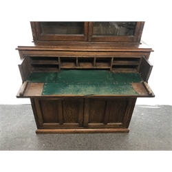  Early 20th century oak bookcase on secretaire, two glazed doors, three shelves above fall front drawer enclosing fitted interior, two cupboards, plinth base, W110cm, H226cm, D40cm  