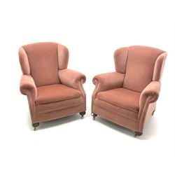Pair early 20th century wing back armchair upholstered in a coral fabric, bun feet on castors
