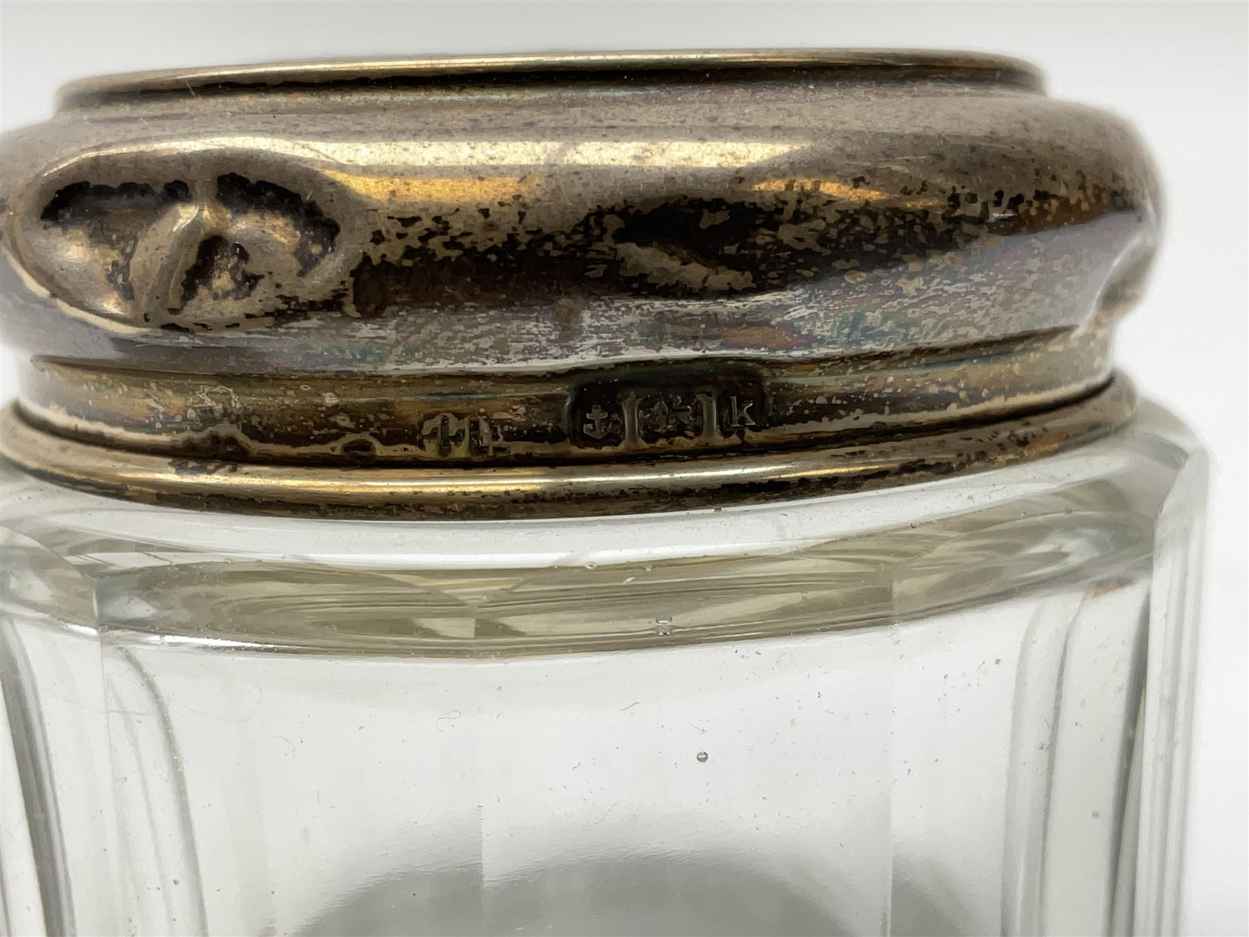 Hallmarked silver top dressing table jars, to include cut glass hobnail example with foliate engraved lid, another 20th century cut glass example with silver engraved screw thread lid, stamped H.S.M Herbert Scott Murdoch, with interior stopper and two smaller glass jars (4)