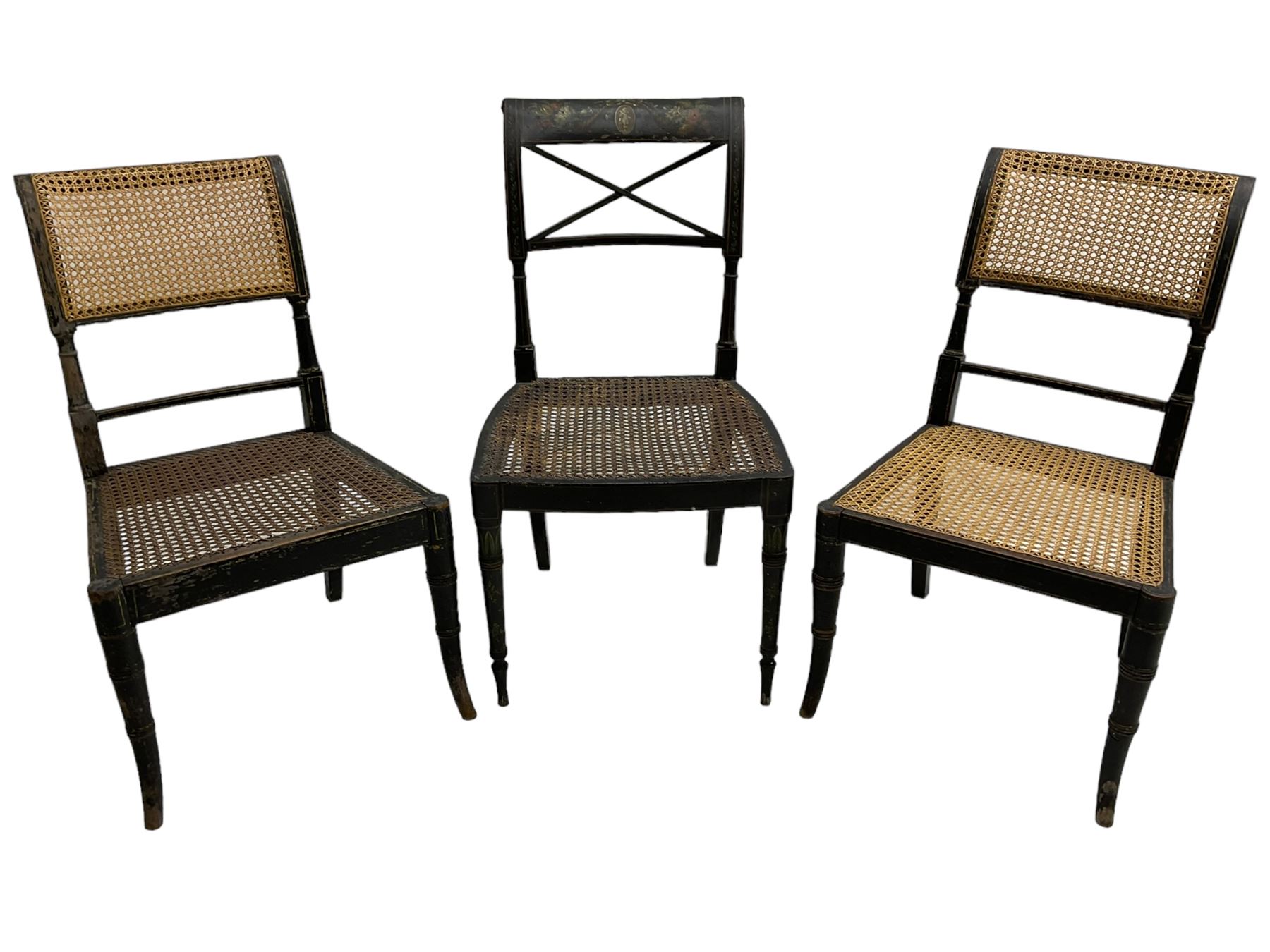 Collection of Regency dining chairs - set of four Regency painted beech dining chairs, with cane seat and back, on collar turned supports with splayed feet (W46cm, H84cm); a pair of Regency ebonised dining chairs (W47cm, H77cm); and a single Regency dining chair, the cresting rail painted with floral cornucopias and central putto vignette, X-frame back over cane seat, on collar turned front supports painted with foliage (W46cm, H84cm) (7)