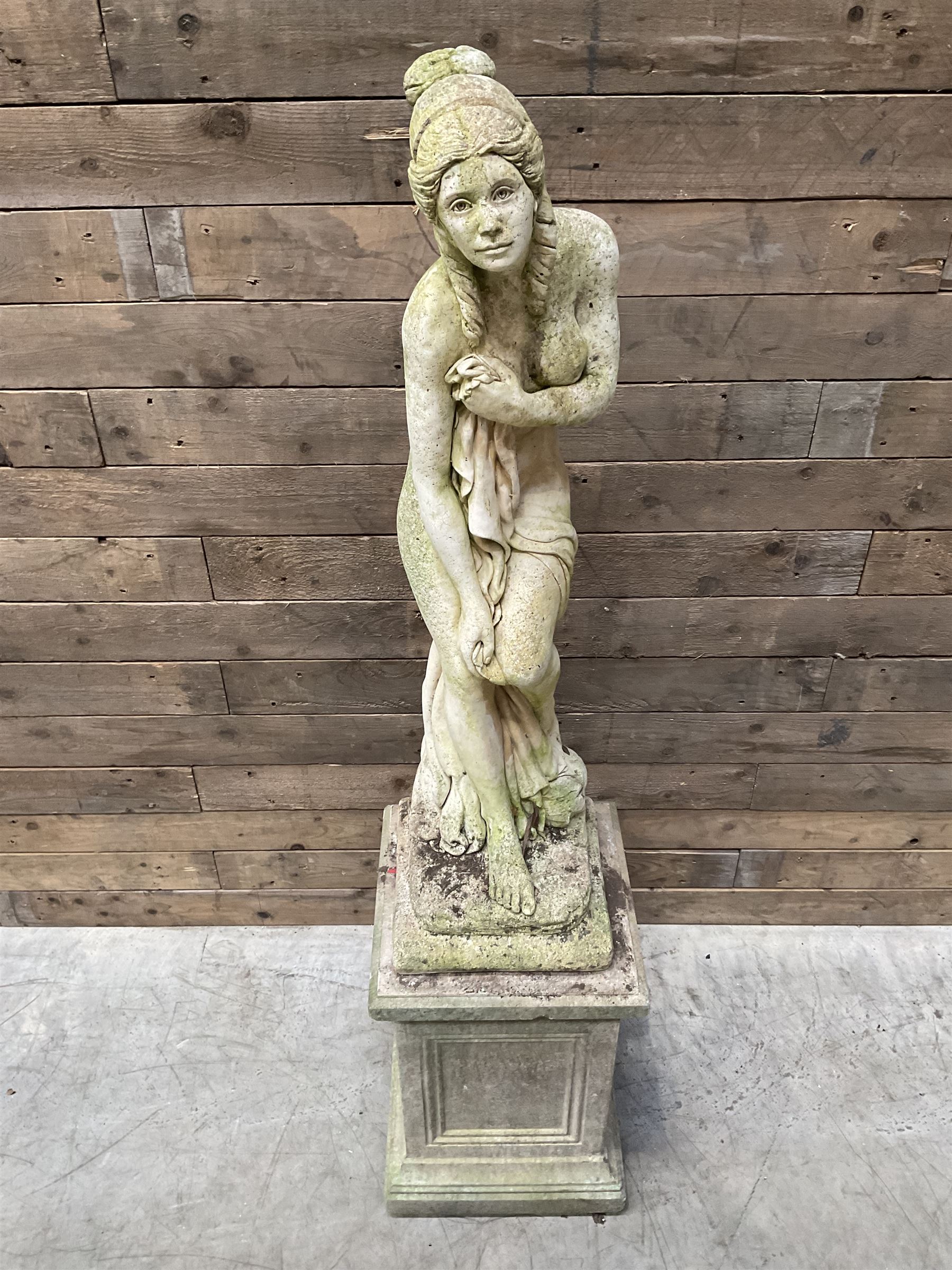 Cast stone garden figure of a bathing lady, raised on square plinth