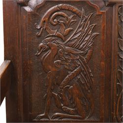 19th century Gothic Revival heavily carved oak settle or hall bench, the high quadruple back with moulded cresting rail over a frieze carved with stylised dolphin and sea creature motifs, the panels decorated with griffin and bird motifs with floral dividing rails, the shaped apron similarly carved with scaly sea beasts, on three cabriole front-supports united by stretchers