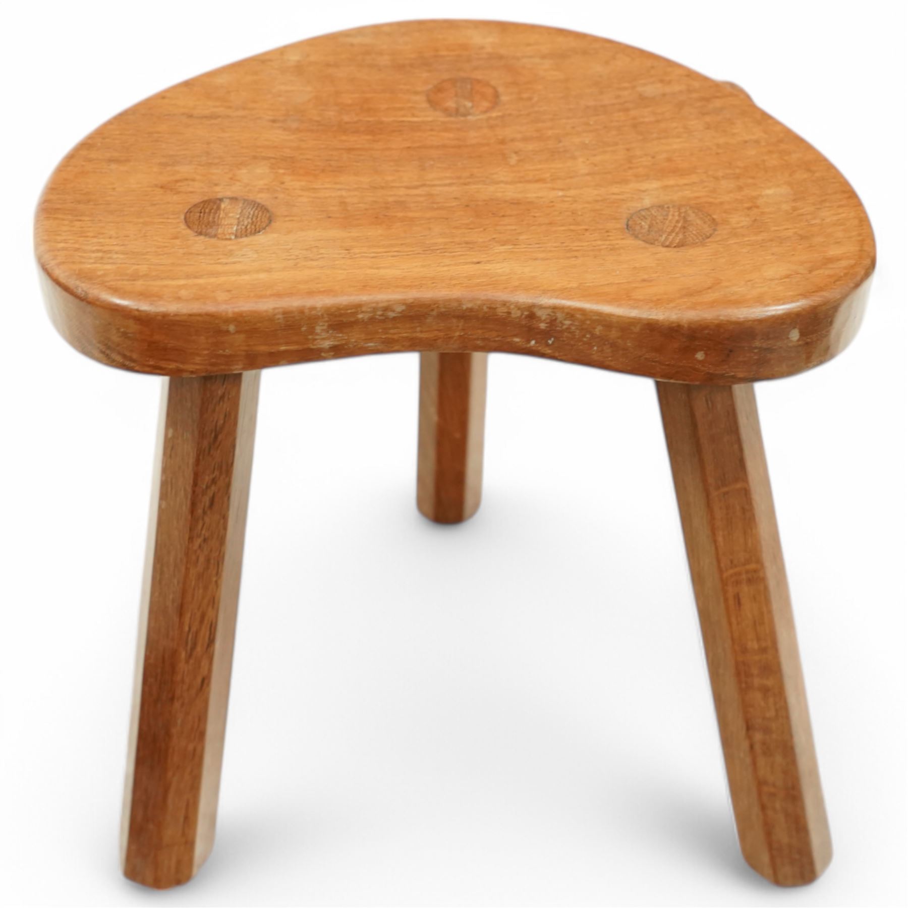 Mouseman - oak three-legged stool, dished kidney-shaped seat on three octagonal splayed supports, carved with mouse signature, by the workshop of Robert Thompson, Kilburn
