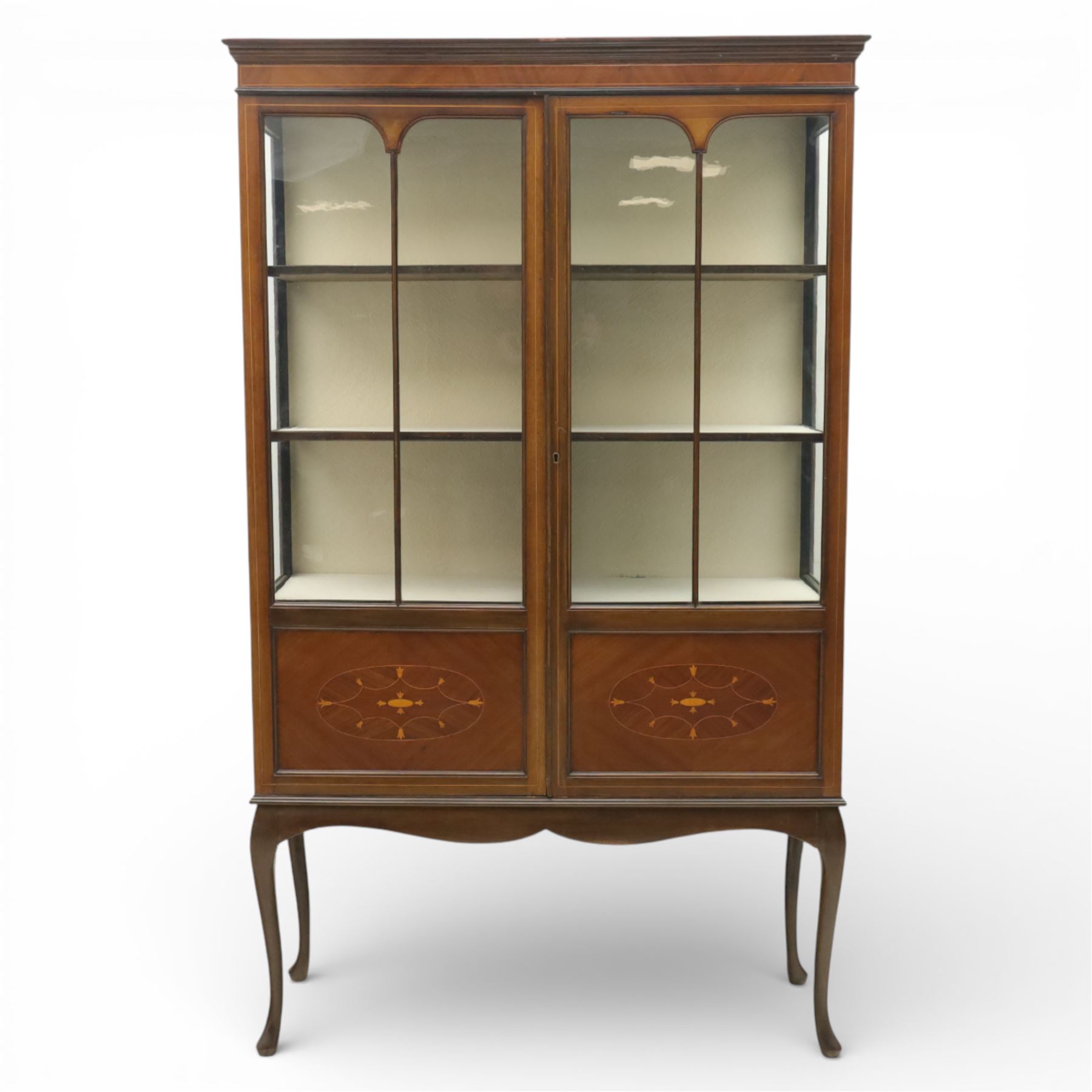 20th century Edwardian style mahogany display bookcase cabinet, the moulded cornice above two lancet glazed doors enclosing a shelved interior, the lower sections with oval inlaid fan decoration, supported on shaped cabriole legs