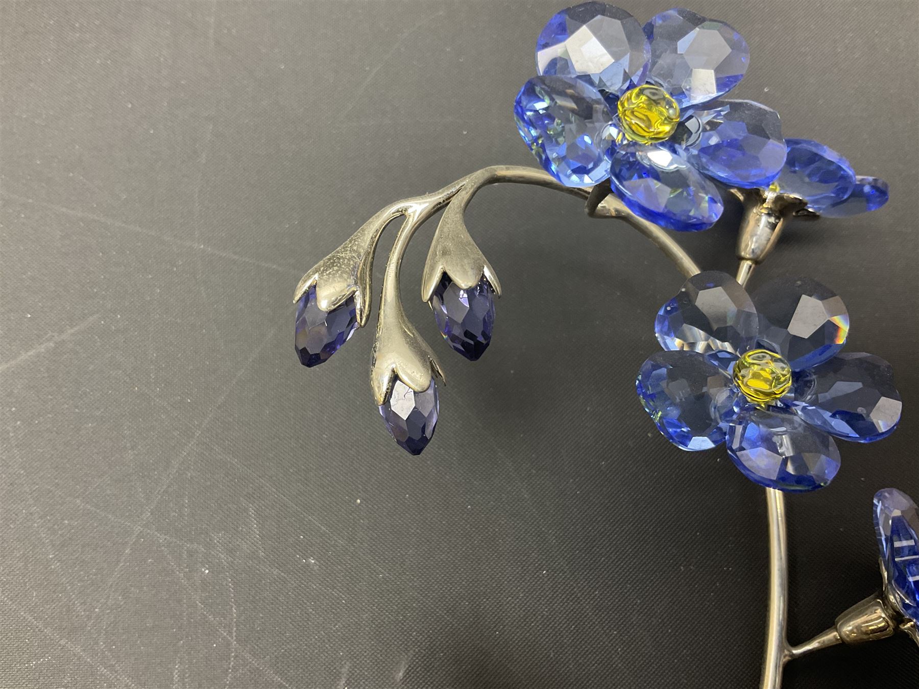 Eleven Swarovski Crystal flowers, to include violet, sunflower, delphinium, forget-me-not and lily-of-the-valley, each on stylised metal stems, tallest H23cm