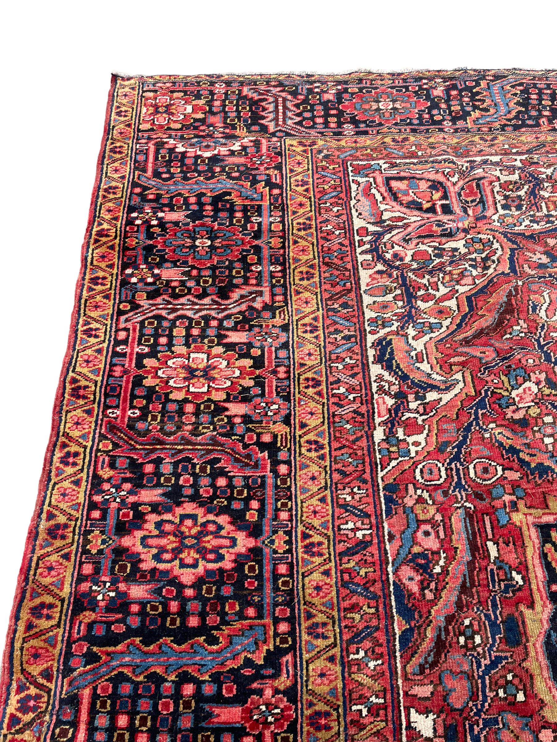 Antique Persian coral ground carpet, the large central floral pole medallion with extending foliate designs, the thick guarded indigo border with repeating flower heads and circles