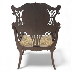 Art Nouveau mahogany open armchair in the manner of Shapland & Petter, the shaped and pierced back with foliate cresting and central panel inlaid with stylised marquetry plume, curved arms over upholstered seat, raised on sabre legs