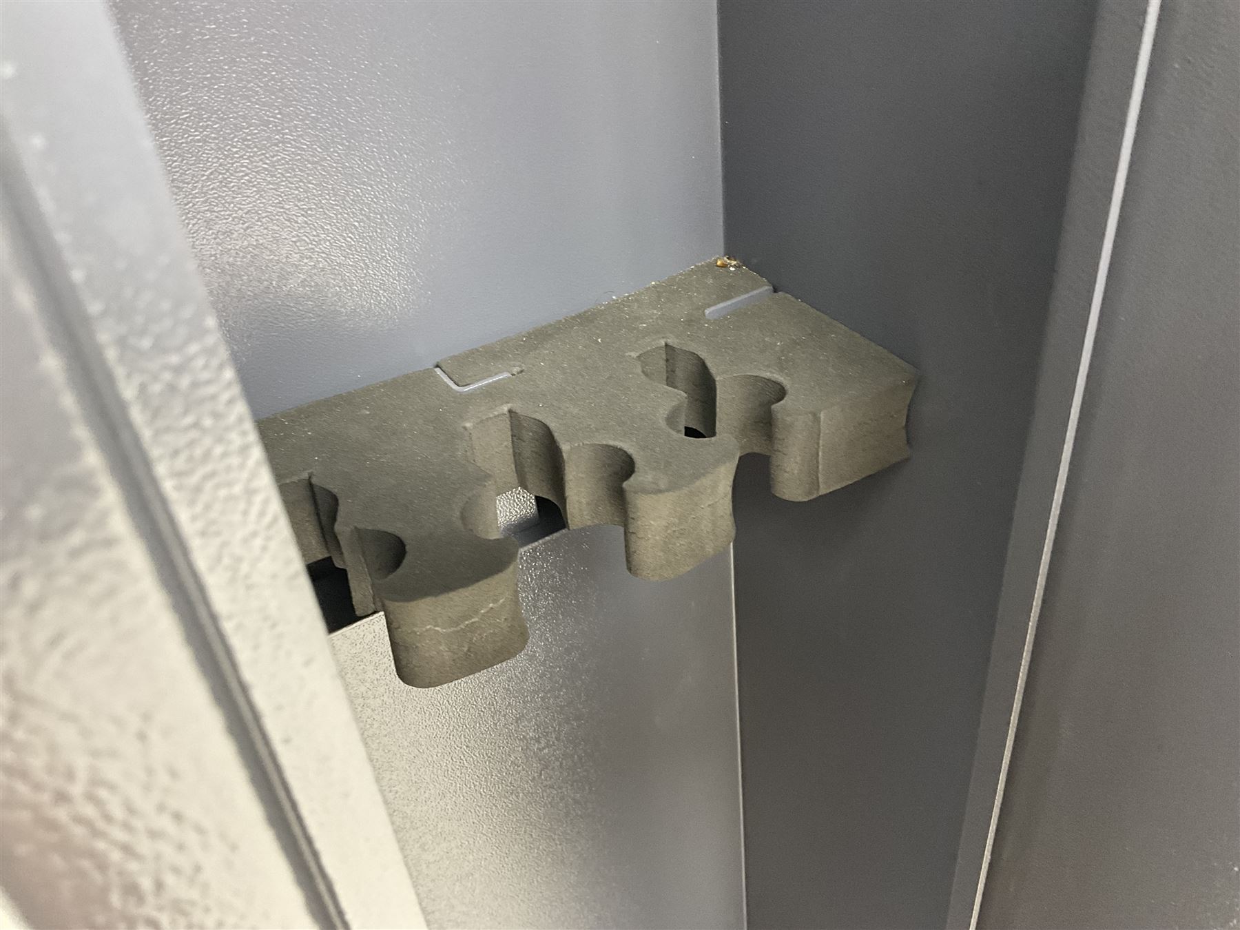 Grey steel wall mounting gun cabinet to accommodate three guns; single door with two locks with two keys for one lock; internally H128.5cm W21cm D17.5cm; externally H129cm W21.5cm D20cm