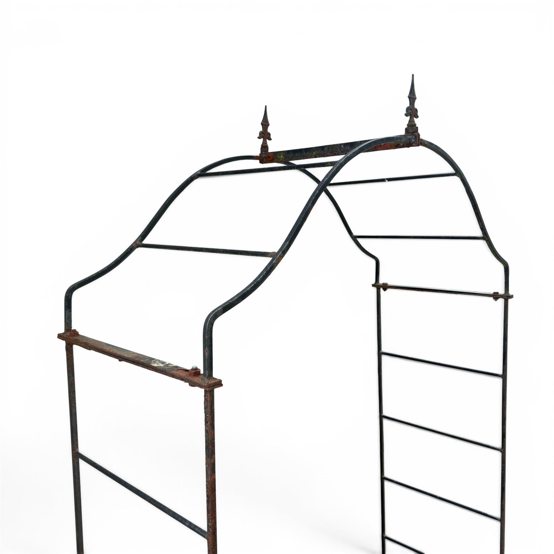 Antique wrought iron strapwork garden arch, with scroll form arched top with spearhead finials, over integral side trellis panels, in distressed black-painted finish