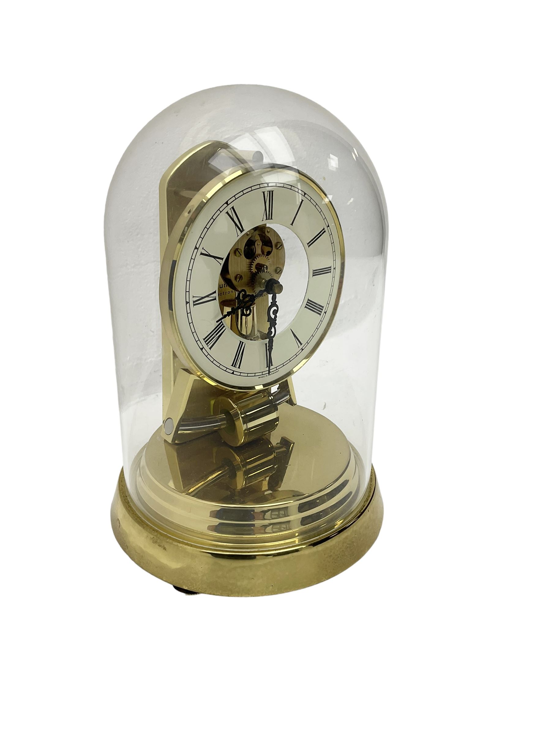  A late 20th century -  German Kieninger & Obergfell, “Kundo” battery operated
mantle clock under an acrylic shade, with an electrically operated solenoid pendulum housed on a circular brass base, skeleton movement with visible motion work through a painted 4-1/2” open chapter ring, with pierced steel hands, Roman numerals and minute track.