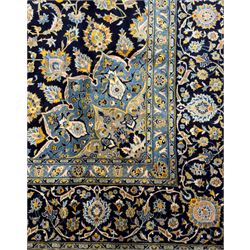 Central Persian Kashan hand-knotted carpet, the navy field with central medallion in pale blue and gold tones, surrounded by spiralling arabesques and palmettes, framed by quarter spandrels and a wide border of stylised lotus and rosette motifs between floral guard stripes, from the region of Kashan
