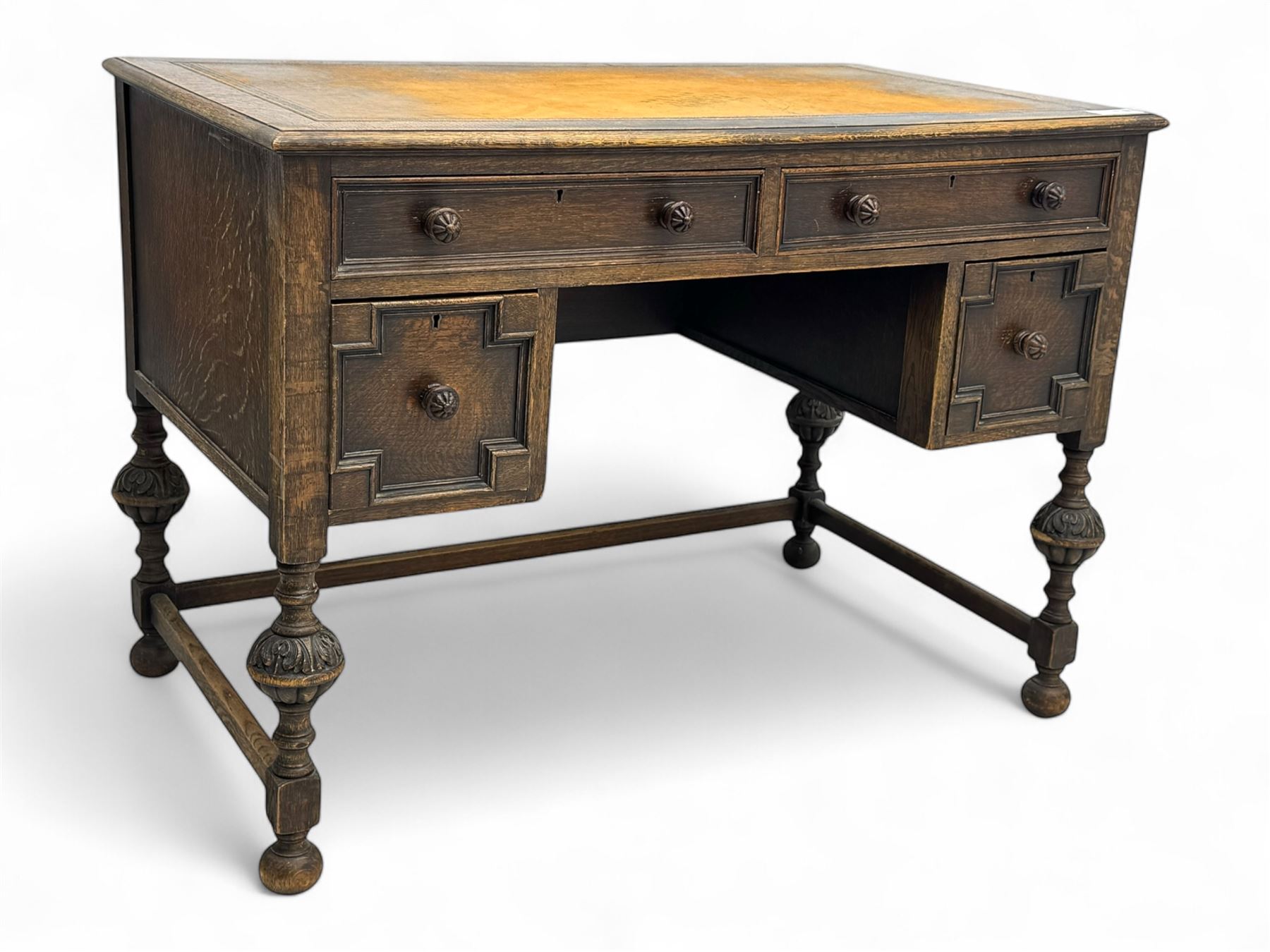 Early 20th century Jacobean design oak desk, with rectangular top inset with worn tooled leather, two frieze drawers over pedestals each fitted with a pair of panelled drawers, turned handles, on carved and fluted tapering legs united by stretchers 