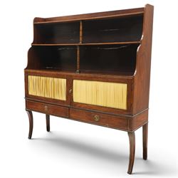 Regency period mahogany waterfall-bookcase chiffonier, the raised back with two open shelves supported by central ring-turned pilasters, fitted with twin doors with sage-green pleated fabric facias, over two drawers with satinwood stringing, raised on front sabre supports