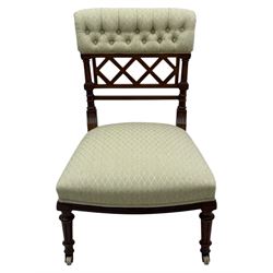 Late Victorian upholstered armchair, with high camel back and deep seat, padded arms and backrest in crimson and cream damask-style fabric, raised on turned ebonised front supports with ceramic castors (H88cm, W65cm, D 60m); and an Edwardian bedroom chair with button upholstered rail back (H72cm, D64cm, W53cm) (2)