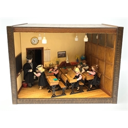 A 1/12th scale diorama of a school room interior, depicting pupils and teacher, the room furnished with panelled wall, desks, chalk board, globe, books and dunces hat, etc., H29cm L40cm D26cm.  
 
This model is based on a Victorian School Room in the museum in Armley, where the children and teachers would dress in period costume and attend lessons during the summer time.