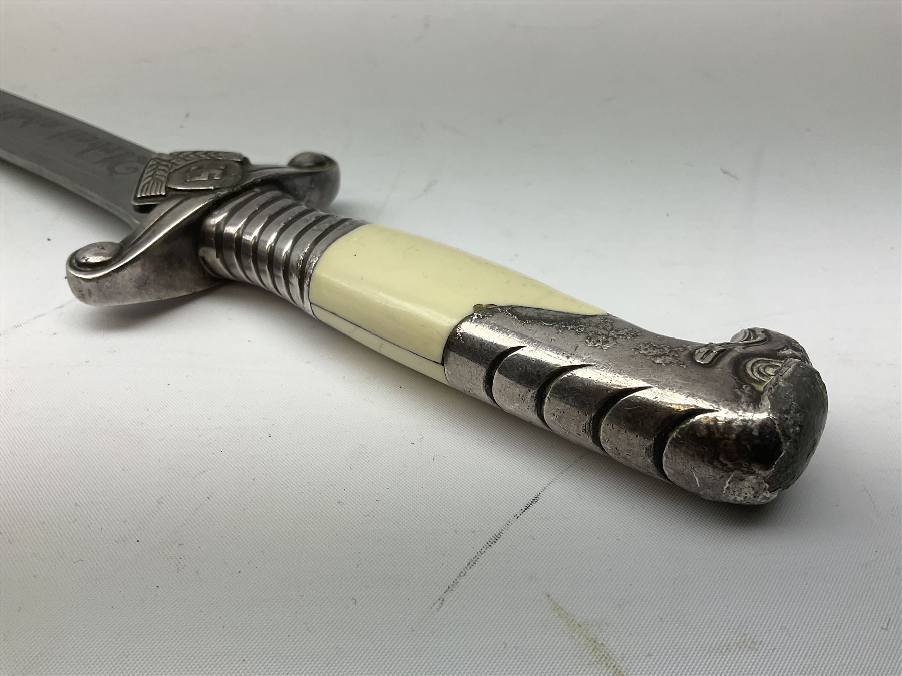 German Reichsarbeitdienst RAD Leader's Hewer dagger, the 26cm single edged scimitar shaped blade with narrow fuller, etched Arbeit adelt; by E.D. Wusthof, Solingen; the aluminium hilt with spade and wheat ear langet; two piece white plastic grip and eagle head pommel; pebbled steel scabbard engraved with ears of wheat and strapwork with double leather hangers L40cm overall